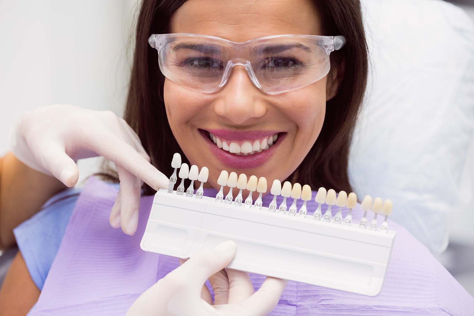 Dentist examining female patient with teeth shades at dental clinic